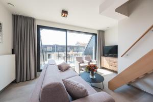 a living room with a couch and a large window at Belcasa Mar Suites & Lofts Aparthotel in Middelkerke