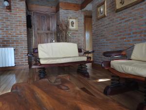a living room with two chairs and a brick wall at Cabañas Kurumamell in Sierra de los Padres
