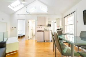 a kitchen with a glass table and chairs in a room at Beautiful 1 Bedroom penthouse Flat in London