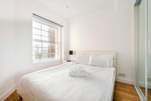 Beautiful 1 Bedroom penthouse Flat في لندن: سرير أبيض في غرفة نوم بيضاء مع نافذة