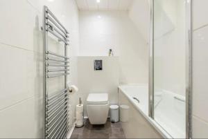 a white bathroom with a toilet and a shower at Beautiful 1 Bedroom penthouse Flat in London
