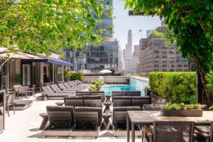 een dakterras met tafels en stoelen en een zwembad bij The Dominick Hotel in New York
