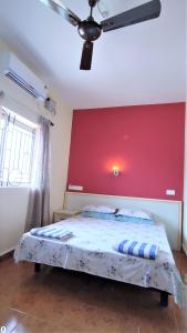 um quarto com uma cama com uma parede vermelha em Monte Villa Guest House em Candolim