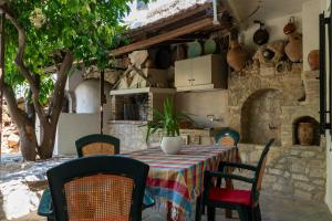 einen Tisch und Stühle in einer Küche mit einer Steinmauer in der Unterkunft House Rachati in Zarós
