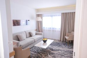 a living room with a couch and a table at Thalazur Ouistreham - Hôtel & Spa in Ouistreham