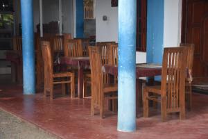 een houten tafel met houten stoelen en een blauwe paal bij Tashil Hotel & Restaurant in Tissamaharama