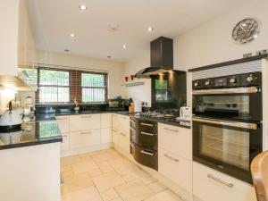 a large kitchen with white cabinets and black appliances at The Lillies in Great Rowsley