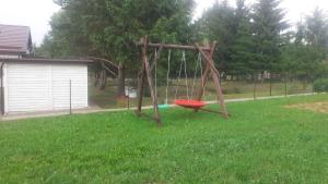 a wooden swing in a yard with a red frisbee at Biały domek nad stawem in Huta Wielka