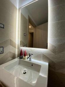 W łazience znajduje się biała umywalka i lustro. w obiekcie Appartamento Gnomo Livigno w Livigno