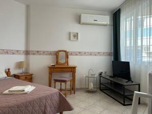 a bedroom with a bed and a television and a desk at Panorama Chantall-izby,apartmány s výhľadom na more in Ravda
