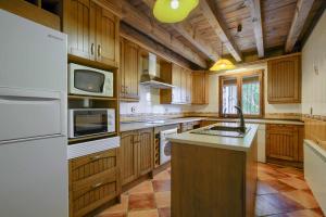 a large kitchen with wooden cabinets and white appliances at Casa rural El Callejón de la Gata in Majaelrayo