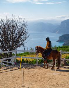 Una donna cavalca un cavallo di fronte a una recinzione di Ghivine Albergo Diffuso a Dorgali