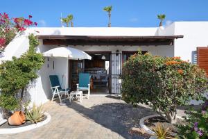a small white house with chairs and an umbrella at Puerto Chico N in Playa Blanca