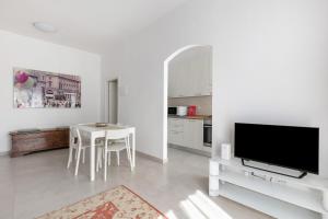 un soggiorno bianco con tavolo e TV di A Casa di Giorgia by Wonderful Italy a Bologna