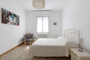 ein weißes Schlafzimmer mit einem Bett und einem Stuhl in der Unterkunft A Casa di Giorgia by Wonderful Italy in Bologna