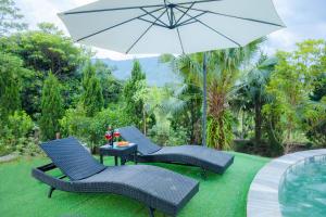 two chairs and a table with an umbrella at Rose Villa in Hòa Bình