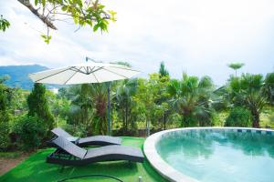 a swimming pool with two chairs and an umbrella at White Villa in Hòa Bình