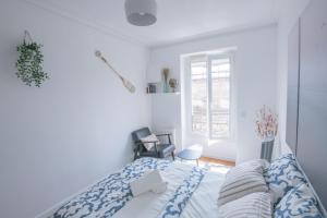 una camera bianca con un letto e una finestra di Paris Bercy - Charming Apartment 2 rooms a Parigi