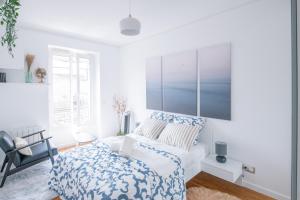 een witte slaapkamer met een bed en een stoel bij Paris Bercy - Charming Apartment 2 rooms in Parijs
