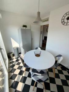 una mesa y sillas blancas en una habitación con suelo a cuadros en Proche tram A: 3 personnes, balcon, wifi gratuit, en Grenoble