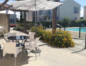 a patio with a table and chairs and an umbrella at Résidence services Les Essentielles Sainte Soulle in Sainte-Soulle