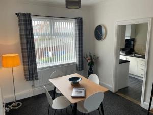 a dining room with a table and chairs and a kitchen at Sandpiper in Hartley