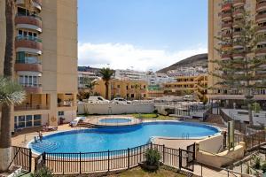 a large swimming pool in a resort with buildings at Estudio Torres del Sol in Playa de las Americas