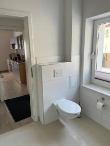 a white bathroom with a toilet and a window at Zum Rosental in Rötha