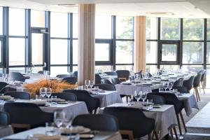 un comedor con mesas, sillas y ventanas en Thalazur Ouistreham - Hôtel & Spa en Ouistreham