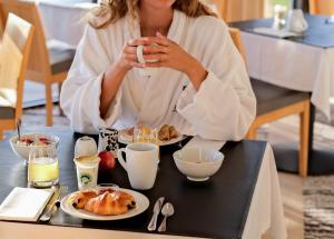 a woman sitting at a table with a plate of food at Thalazur Ouistreham - Hôtel & Spa in Ouistreham