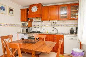 a kitchen with a wooden table and a clock on the wall at Apartamento Joana Vasconcelos, Ocean view & Pool - Pata da Gaivota in Lourinhã