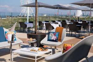 a patio with chairs and tables and umbrellas at Thalazur Ouistreham - Hôtel & Spa in Ouistreham