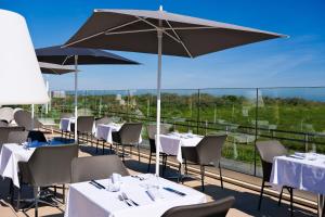 a restaurant with tables and umbrellas on a balcony at Thalazur Ouistreham - Hôtel & Spa in Ouistreham