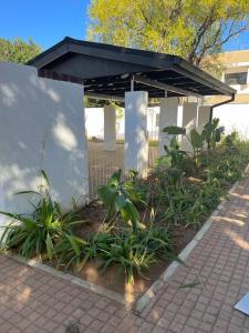 a pavilion with a black roof and plants at Comfy Zone Apartment in Gaborone
