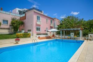 a swimming pool in front of a pink house at Apartamento Joana Vasconcelos, Ocean view & Pool - Pata da Gaivota in Lourinhã