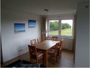 a dining room table with chairs and a large window at Fehmarn-OstseeferienSeeblick204 in Fehmarn