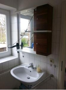 baño con lavabo, espejo y ventana en Fehmarn-OstseeferienSeeblick204, en Fehmarn