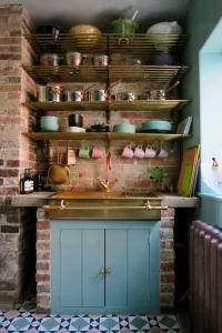 a kitchen with pots and pans on a brick wall at Monastery Cottage in Rye