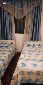 2 camas en una habitación con cortinas azules en Front Seaview Villa At Flic En Flac en Palmyre