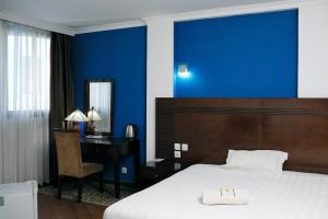 a bedroom with a blue wall and a bed and a desk at Central Hotel Tana in Antananarivo