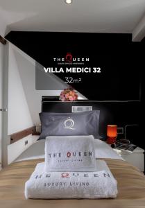 a bed with a sign that reads the queen villa medici at The Queen Luxury Apartments - Villa Medici in Luxembourg