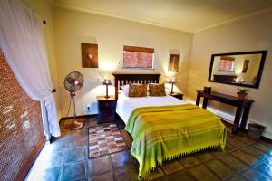 a bedroom with a bed and a fan at Otjiwa Safari Lodge in Otjiwarongo