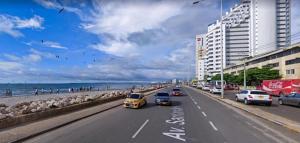 una calle con coches conduciendo por una carretera junto a la playa en Apartamento cerca al Centro Histórico en Edificio frente a la playa A-3-5, en Cartagena de Indias