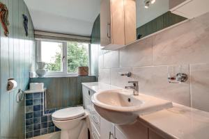 a bathroom with a sink and a toilet and a window at Meadow Cottage in Bicester