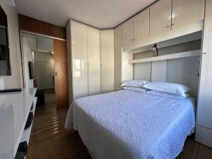 a bedroom with a bed with a blue comforter at Edificio Long Beach in Balneário Camboriú