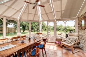 einen großen Wintergarten mit einem großen Holztisch und Stühlen in der Unterkunft Meadow Cottage in Bicester