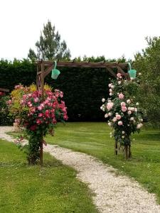 zwei Blumenkörbe auf Pfosten im Gras mit Garten in der Unterkunft Le chêne blanc in La Genétouze