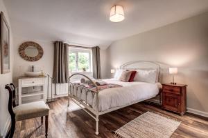 a bedroom with a bed and a chair and a window at Meadow Cottage in Bicester