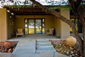 a porch of a house with two chairs and a tree at Otjiwa Safari Lodge in Otjiwarongo