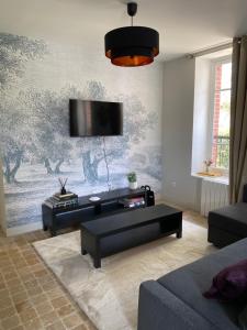 ein Wohnzimmer mit einem Sofa und einem TV an der Wand in der Unterkunft Pavillon époque Napoléon III in Maurecourt